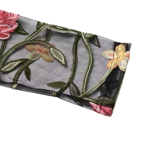 Detail of colorful floral embroidery on black mesh fabric with intricate needlework