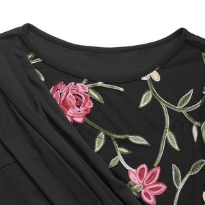 Detail of floral embroidery and pleated texture on a black long-sleeved mesh dress