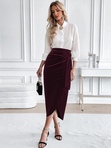 Detail of burgundy velvet midi skirt featuring elegant waist twist and stylish side slit