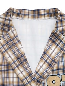 Detailaufnahme von Karomuster-Revers und Stickerei auf hochwertigem Webstoff