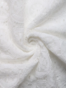 Dettaglio del tessuto in pizzo bianco elegante con ricami floreali in stile bohémien