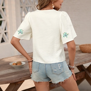 Back view of white tie-back shirt with floral embroidery on sleeves and puff design