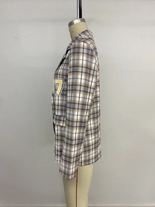 Detail eines karierten Blazers mit gelbem Nummer 7 Aufnäher und braunem Karomuster
