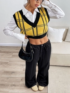 Detail of yellow and black checkered knit vest featuring a V-neck and short crop cut