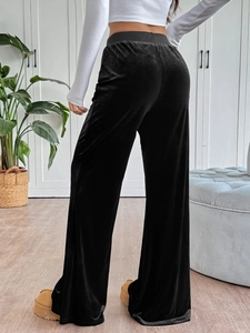 Macro detail of high-waist black velvet flare trousers with elegant draping and glossy texture