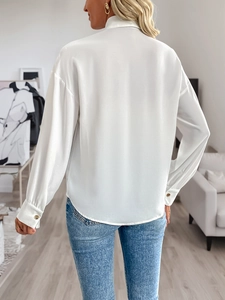 Rear view of a white satin shirt featuring a high collar and gold buttoned cuffs