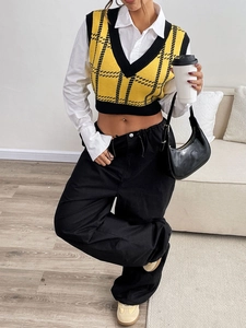 Detail shot of yellow plaid knit vest paired with white shirt and black wide-leg trousers