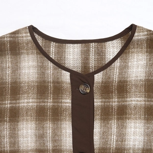 Dettaglio del cardigan in flanella a quadri marroni con scollo tondo e bottone marmorizzato