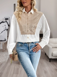Detailed shot of white shirt featuring intricate gold sequins and metallic buttons