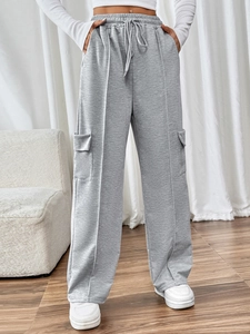 Detail of grey wide-leg joggers featuring elastic drawstring waist and side cargo pockets
