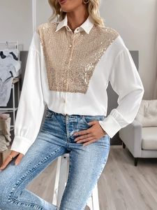 Close-up of sparkling gold sequins and gold buttons on a white long-sleeve blouse