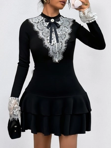 Détail du col en dentelle blanche en V avec nœud noir sur une robe noire élégante