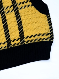 Detail of yellow and black checkered knit vest showing woven texture and ribbed hem