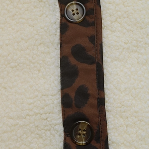 Detailed macro view of fleece coat texture with leopard print placket and tortoiseshell buttons