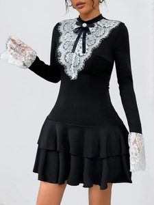 Détail d'une robe noire moulante avec dentelle blanche et nœud orné d'une perle chic
