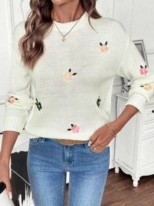 Close-up of floral embroidery on cream knit sweater with ribbed cuffs and round neck