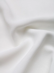 Detailed macro view of white sequin shirt fabric showing smooth texture and soft drape