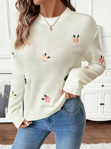 Detailed view of the fine knit texture and floral embroidery on a white crewneck sweater