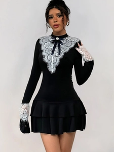 Détail du corsage en dentelle blanche avec nœud noir et perle sur une mini-robe vintage