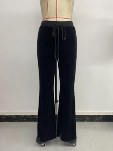 Detail of high-waist black velvet flare pants with adjustable drawstring and metal tips