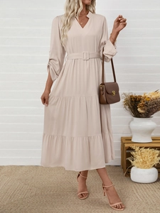 Detail of elegant V-neck midi dress featuring a matching buckled belt and layered skirt hem