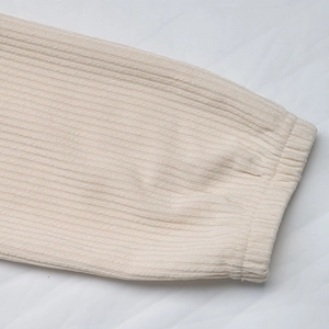 Gros plan des poignets en maille côtelée du pull beige avec texture élastique détaillée