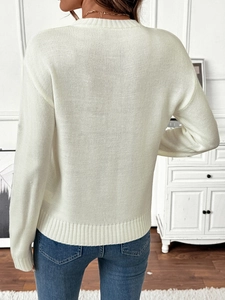 Rear view of a white crewneck knit sweater with ribbed cuffs in a minimalist home setting