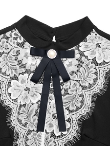 Détail de robe noire avec col en dentelle de cils blanche et ornement nœud avec perle