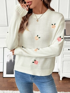 Close-up of beige knit sweater with colorful flower embroidery and ribbed cuffs