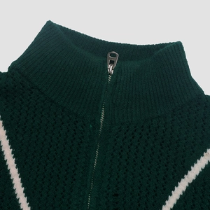 Gros plan détaillé du pull en maille vert foncé avec demi-zip argenté et motif en V