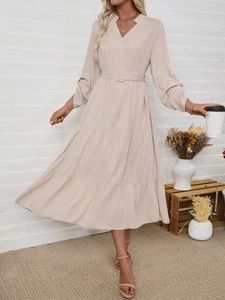 Detail of elegant beige maxi dress with V-neckline, waist belt and tiered cake skirt