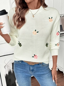 Detail shot of delicate floral embroidery on cream-colored knit sweater with soft texture