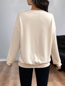 Detail view of the ribbed cuffs and dropped shoulder seams on a beige crewneck sweatshirt