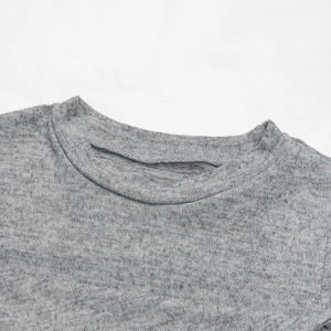 Detail of grey knitted T-shirt showing crew neckline and ribbed texture on white fabric