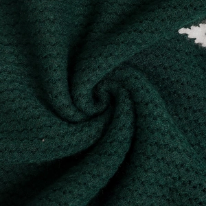 Gros plan sur la maille épaisse vert foncé avec motif flocon de neige en jacquard blanc