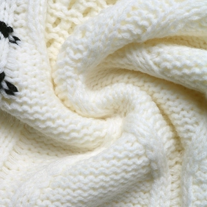 Dettaglio ravvicinato della morbida maglia grossa crema con motivo a contrasto nero