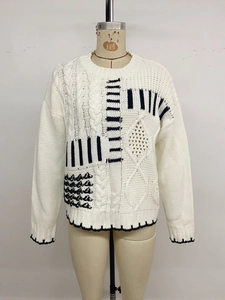 Dettaglio maglione a maglia grossa con motivi geometrici neri e trame a treccia