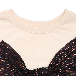 Close-up of beige crew neck sweatshirt with sequined black bow and logo detail