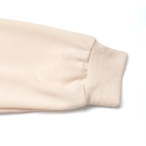 Close-up of cream ribbed cuffs on a minimalist loose-fit long-sleeve sweatshirt
