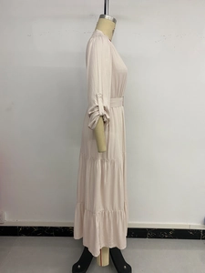 Detail of elegant beige tiered maxi dress featuring long sleeves and buttoned cuffs