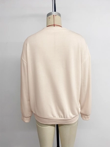 Detail view of the back of a beige oversized sweatshirt with ribbed cuffs and hemline