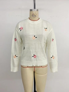 Detailed close-up of sweet flower embroidery on a white knit long-sleeve sweater