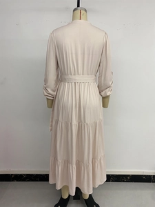 Detail of tiered maxi dress in beige with long sleeves and elegant waist tie belt