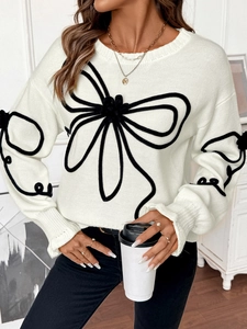 Détail d'un pull en maille blanche avec motifs floraux noirs et texture douce
