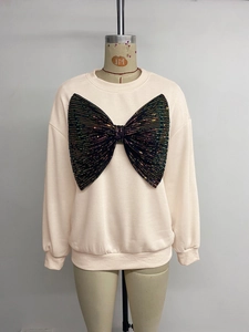 Detail of oversized sweatshirt featuring a large black sequin bow and ribbed cuffs