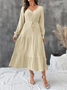 Detail of the V-neckline with hollow lace and button down front on a beige midi dress