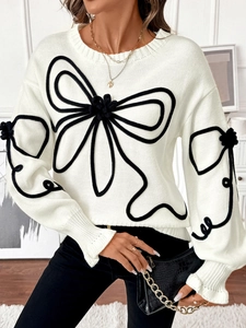 Détail de la broderie en relief fleurie sur un pull en maille torsadée blanc crème