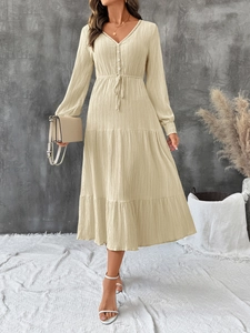 Detail of cream V-neck midi dress with textured fabric, lace trim, and tiered skirt