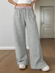 Dettaglio dei pantaloni sportivi grigi con elastico in vita a quadri rossi e coulisse bianca