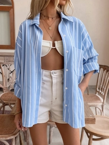 Detail of light blue striped oversized shirt with chest pocket and white buttons